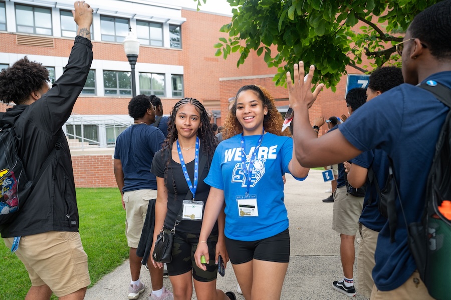 Two students walking by cheering students