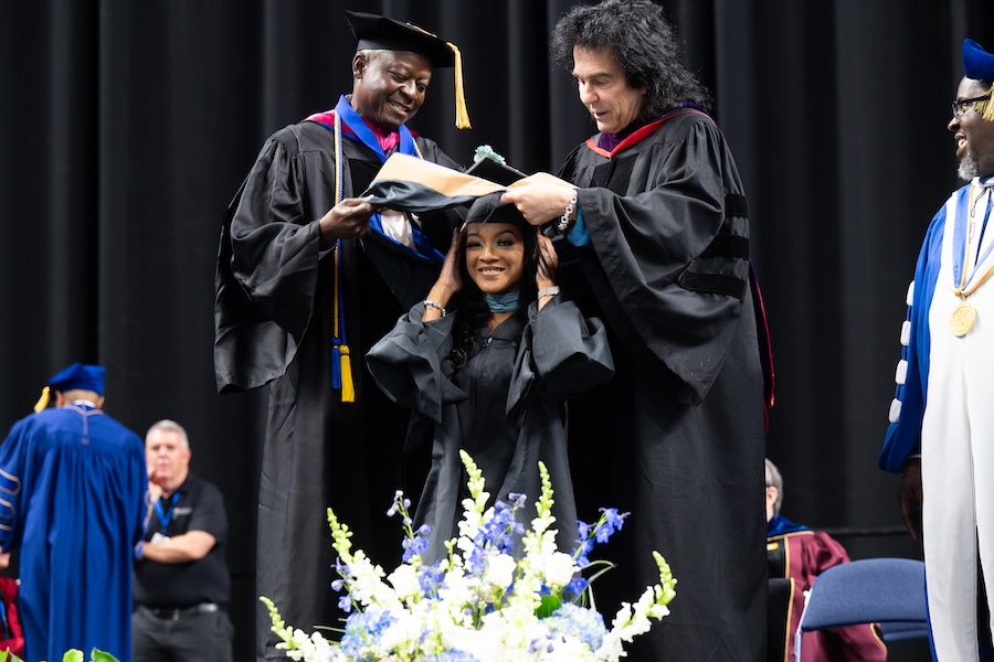 A student in cap and gown at the podium during graduation ceremony