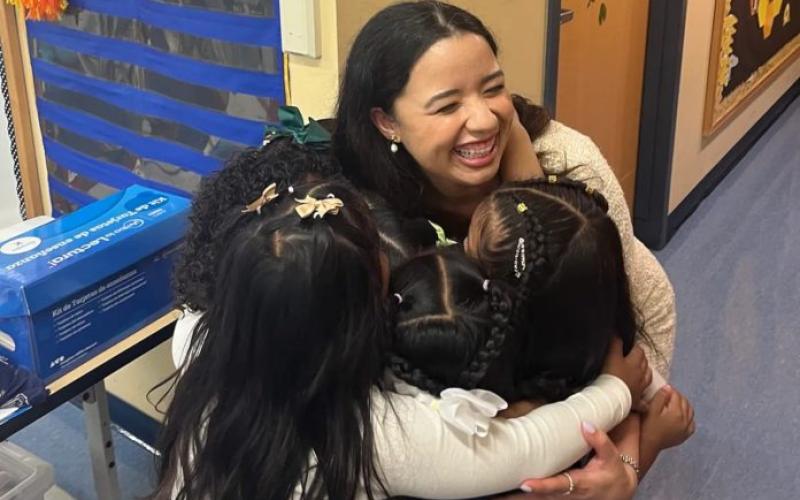 Students hugging student teacher